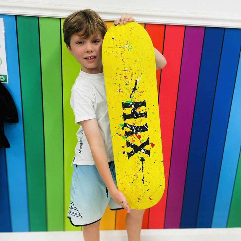 Child holding a yellow skateboard from a skateboard deck party at DIY Invasion